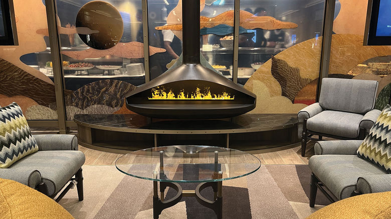 A water-vapor "fireplace" in the Seabourn Pursuit's cozy Exploration Lounge; behind it is a panel that nods to the ship's deployment.
